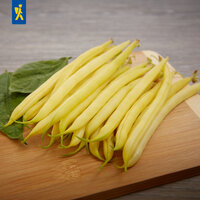 Gelbe Buschbohnen liegen neben grünen Blättern auf einem Holzbrett 