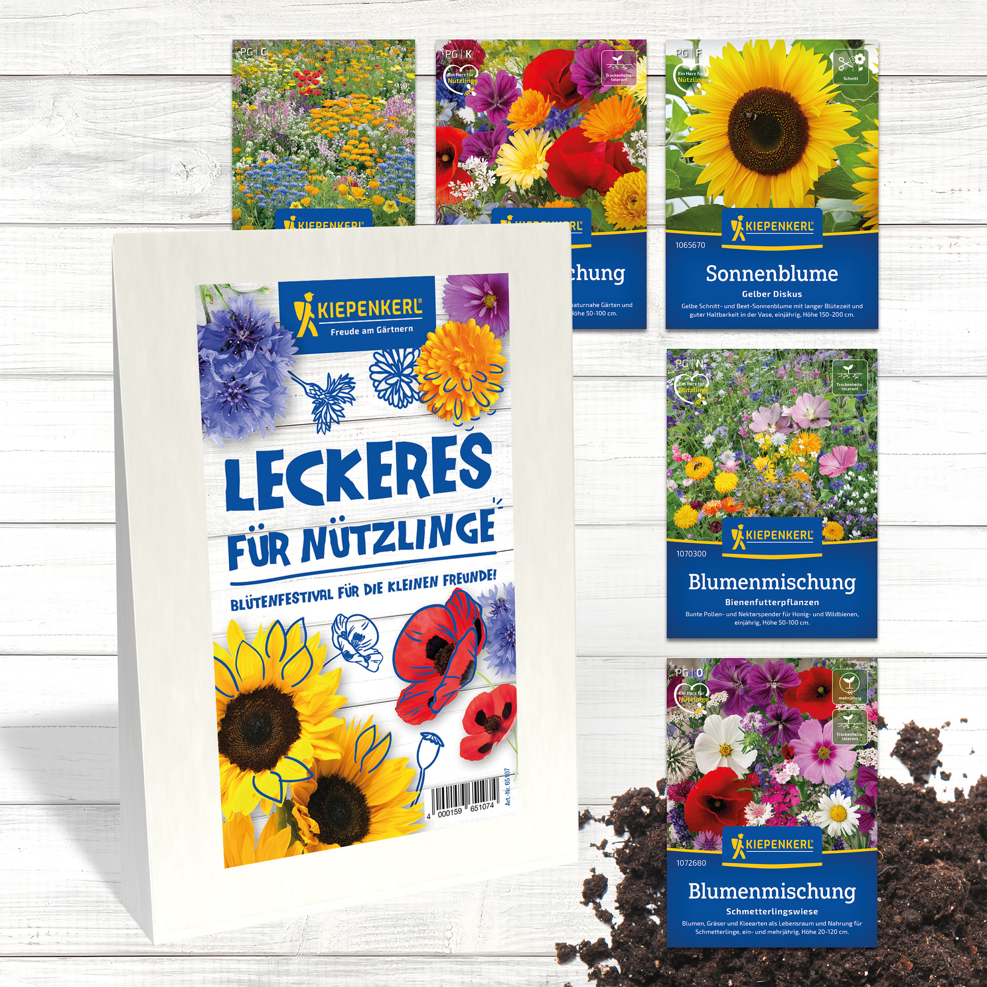 Verschiedene Blumen- und Blumensamenpackungen auf einem weißen Holztisch, mit Erde im Vordergrund.