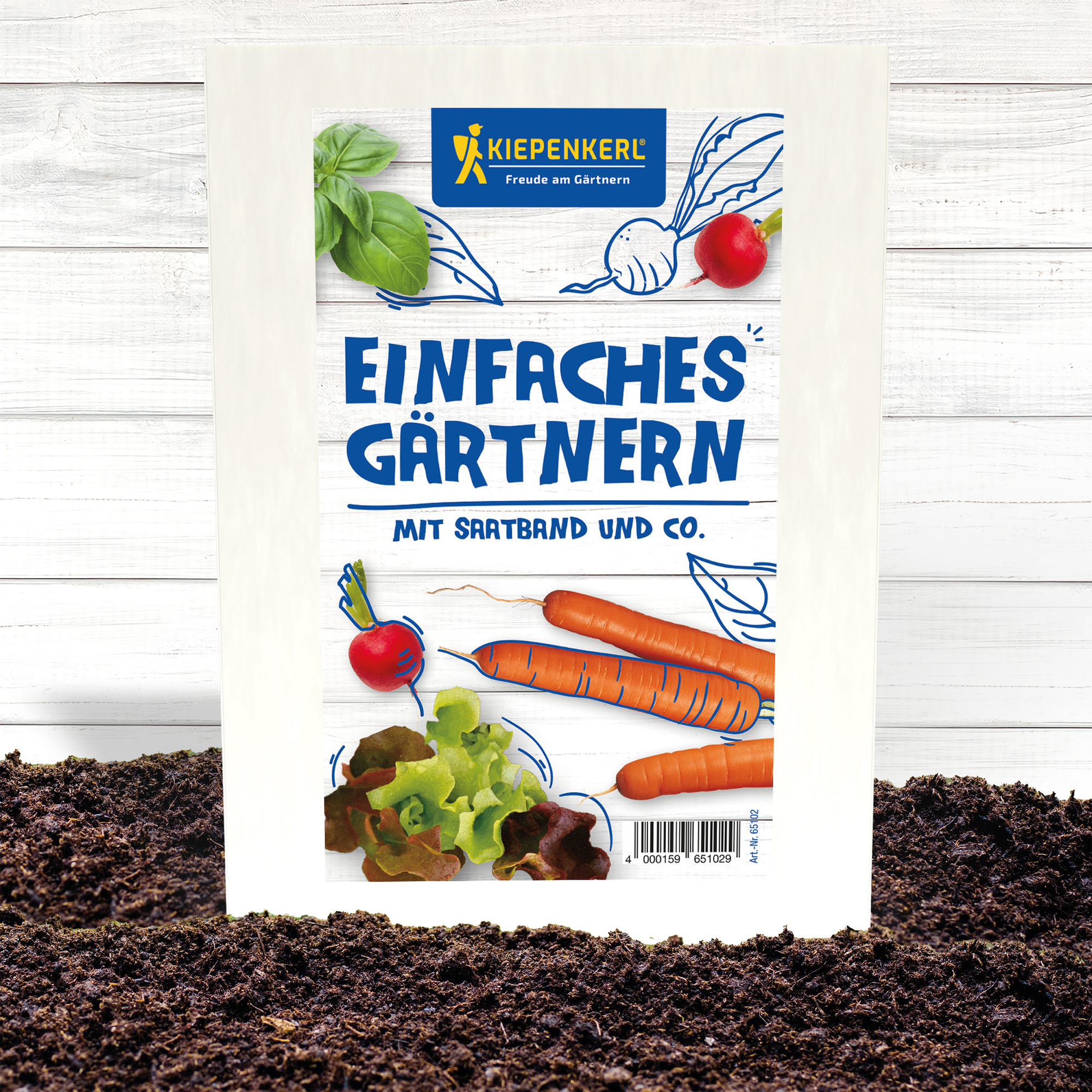 Saatring mit Karotten, Radieschen und Salat auf Erde vor weißem Holz