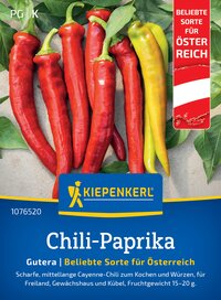 Chili-Paprika in Rot und Gelb mit grünen Blättern auf Steinboden.