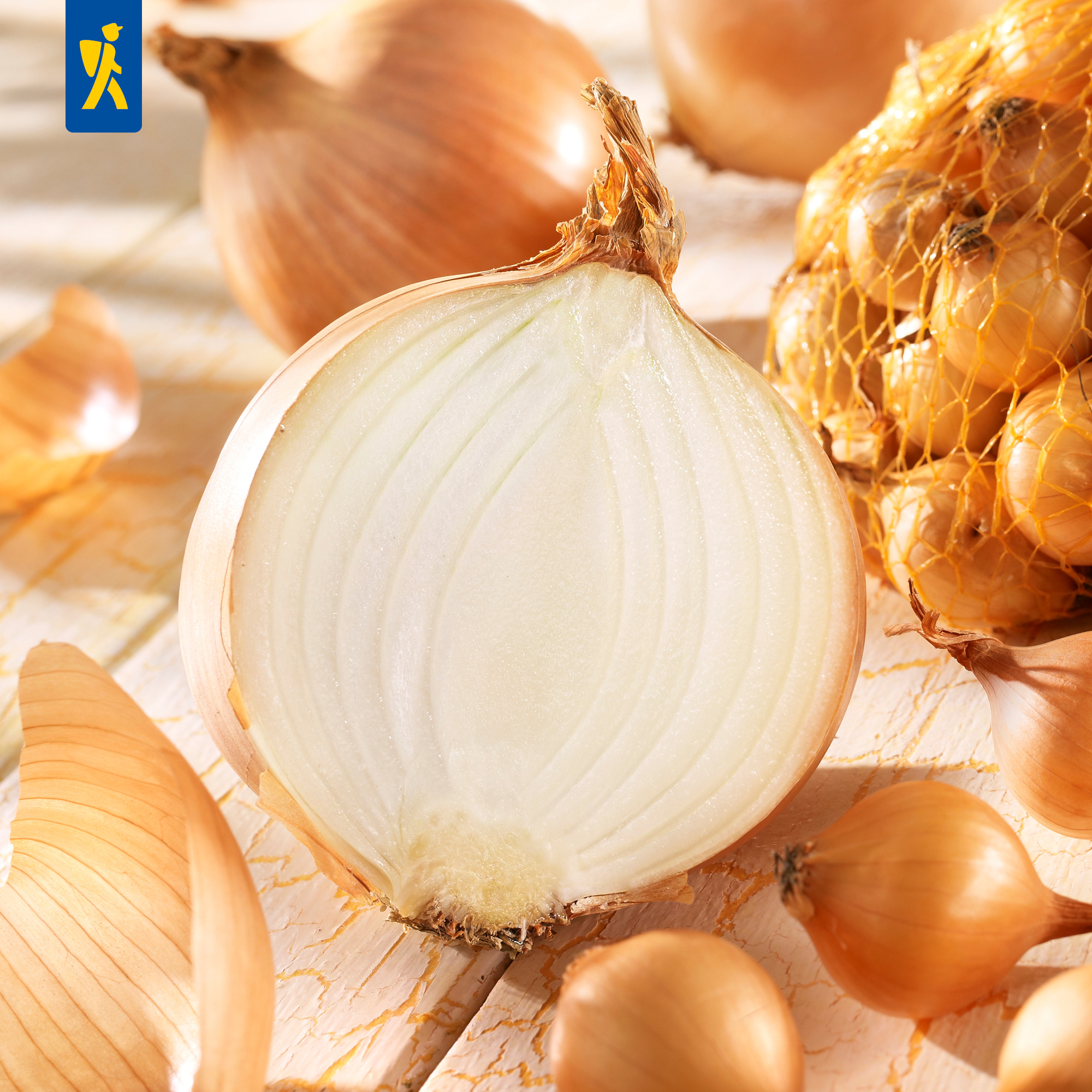 Zwiebeln in Netzbeutel und lose auf einem weißen, weckenden Holztisch.