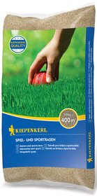 Hand hält rot-weißen Cricketball auf grünem Rasen, Verpackung mit blauer Etikette und Gelb.