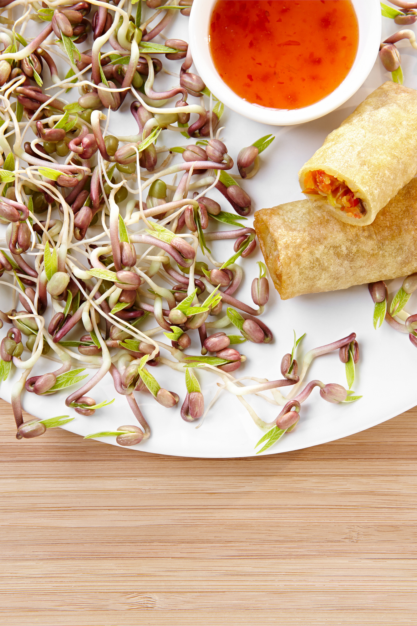 Mungobohnen, Frühlingsrolle mit Dip auf weißen Teller, Holzuntergrund