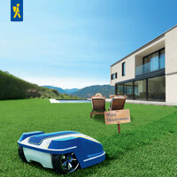 Roboterauto auf gras, zwei sitzende Personen auf Liegen und ein Holzschild mit „Mein Paradiesrasen“ vor einem modernen Haus.